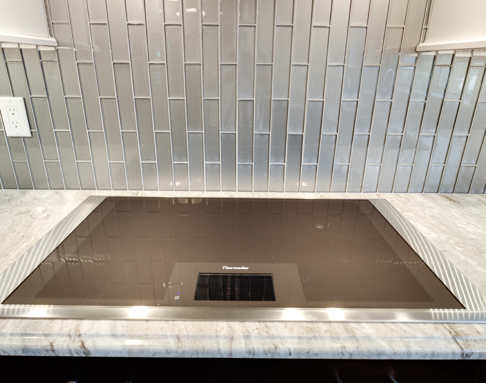 Photo of a contemporary u-shaped enclosed kitchen in DC Metro with a submerged sink, granite worktops, glass tiled splashback, stainless steel appliances, medium hardwood flooring and an island.
