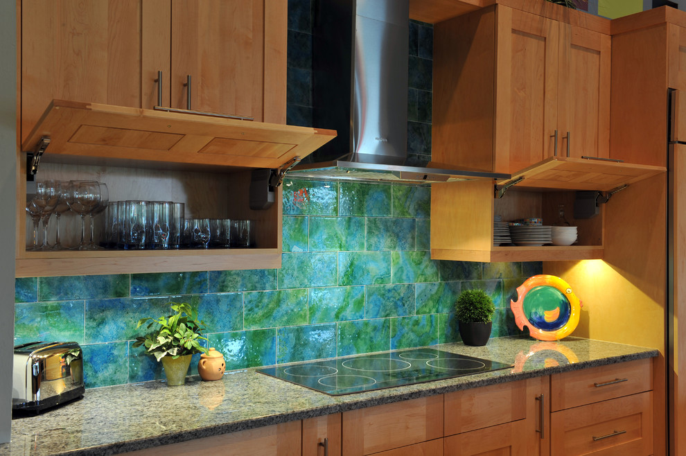 Modern inredning av ett l-kök, med skåp i ljust trä, en köksö, en undermonterad diskho, skåp i shakerstil, granitbänkskiva, blått stänkskydd, stänkskydd i glaskakel, rostfria vitvaror, klinkergolv i porslin och beiget golv
