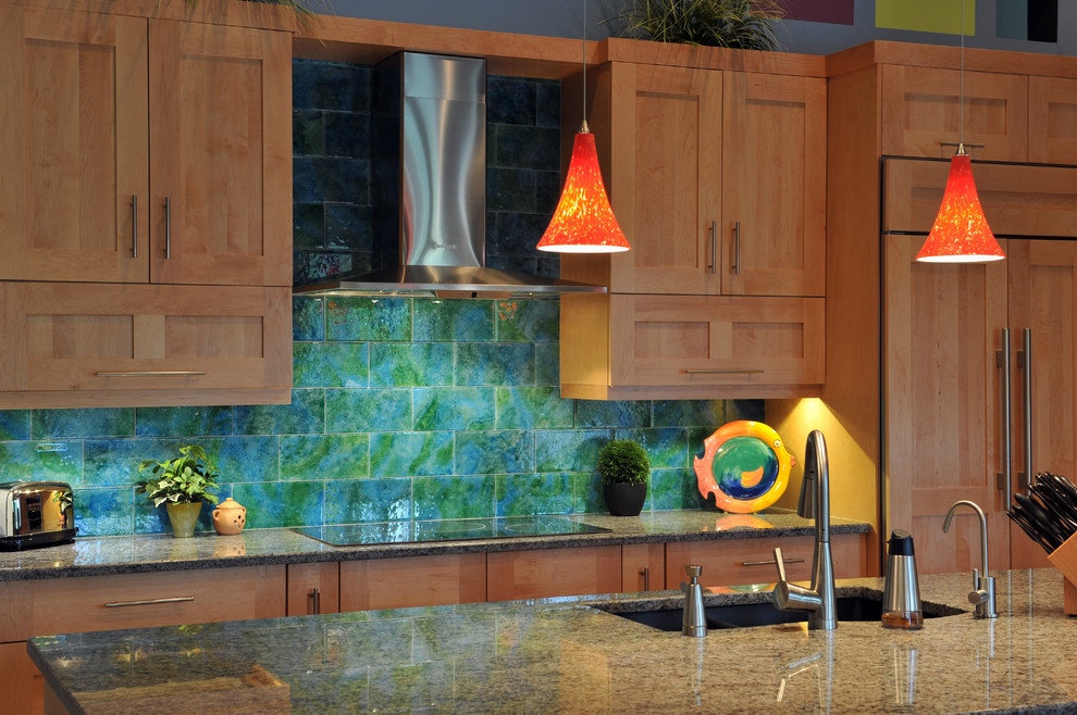 Modern inredning av ett l-kök, med en undermonterad diskho, skåp i ljust trä, rostfria vitvaror, en köksö, skåp i shakerstil, granitbänkskiva, blått stänkskydd, stänkskydd i glaskakel, klinkergolv i porslin och beiget golv