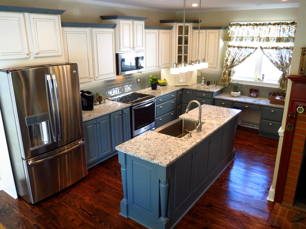 This is an example of a large rural kitchen in DC Metro with a belfast sink, raised-panel cabinets, beige cabinets, granite worktops, blue splashback, metro tiled splashback, stainless steel appliances, medium hardwood flooring and an island.