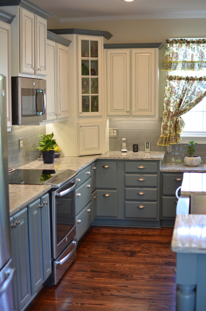 This is an example of a large farmhouse grey and cream kitchen in DC Metro with a belfast sink, raised-panel cabinets, beige cabinets, granite worktops, blue splashback, metro tiled splashback, stainless steel appliances, medium hardwood flooring and an island.