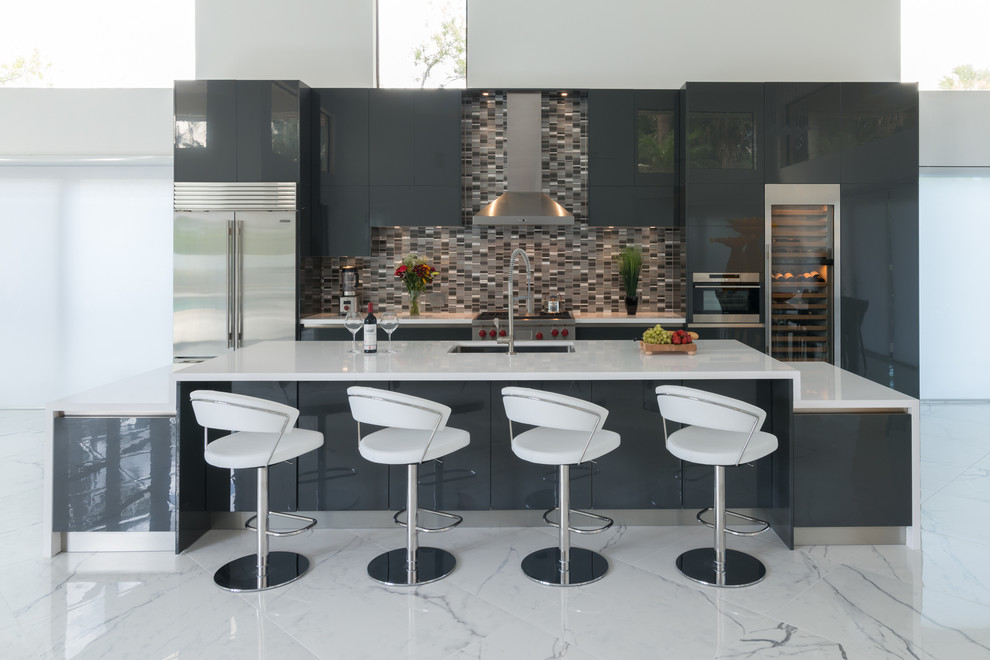 Пример оригинального дизайна: большая параллельная кухня в современном стиле с врезной мойкой, плоскими фасадами, серыми фасадами, разноцветным фартуком, фартуком из плитки мозаики, техникой из нержавеющей стали, островом, обеденным столом, столешницей из кварцевого агломерата и полом из керамогранита