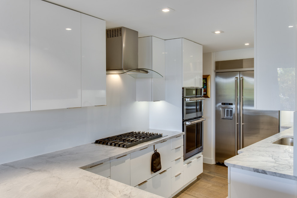 Inspiration for a medium sized contemporary kitchen in DC Metro with a submerged sink, white cabinets, granite worktops, white splashback, stainless steel appliances and a breakfast bar.