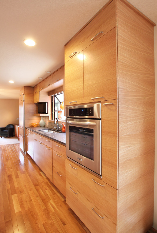Zweizeilige, Mittelgroße Moderne Wohnküche mit Triple-Waschtisch, flächenbündigen Schrankfronten, hellen Holzschränken, Granit-Arbeitsplatte, Küchengeräten aus Edelstahl, hellem Holzboden und Kücheninsel in Minneapolis