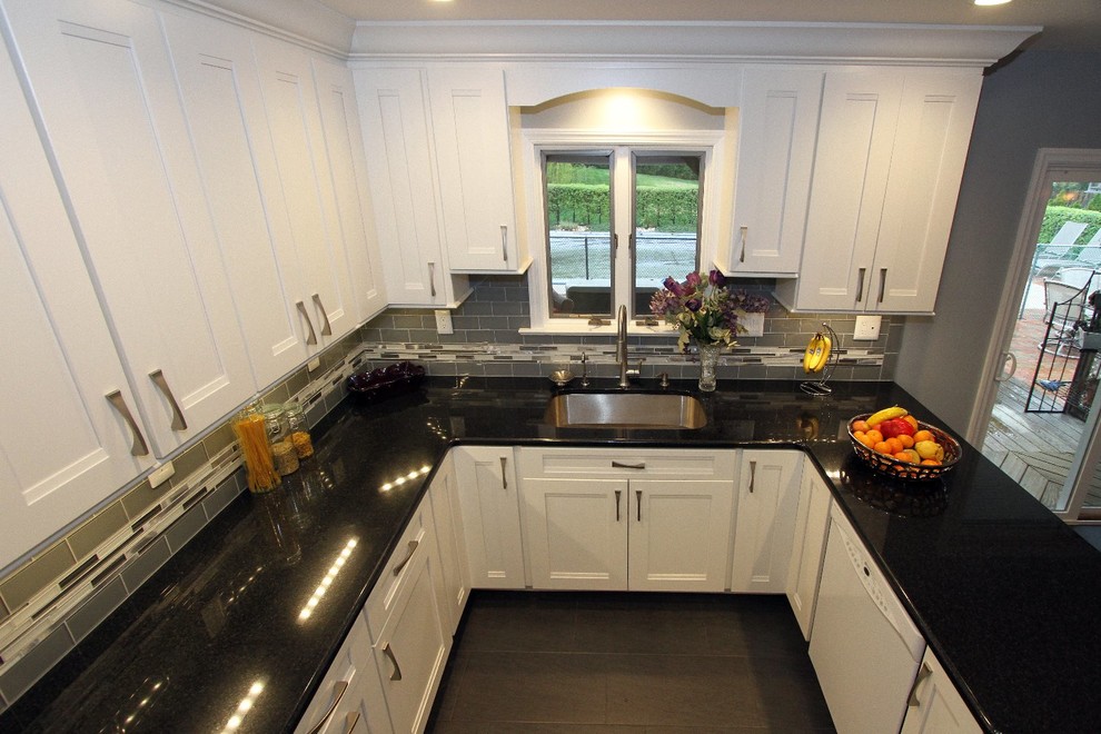Idéer för att renovera ett mellanstort funkis kök, med en enkel diskho, luckor med infälld panel, vita skåp, granitbänkskiva, grått stänkskydd, stänkskydd i glaskakel, rostfria vitvaror, klinkergolv i porslin och en halv köksö