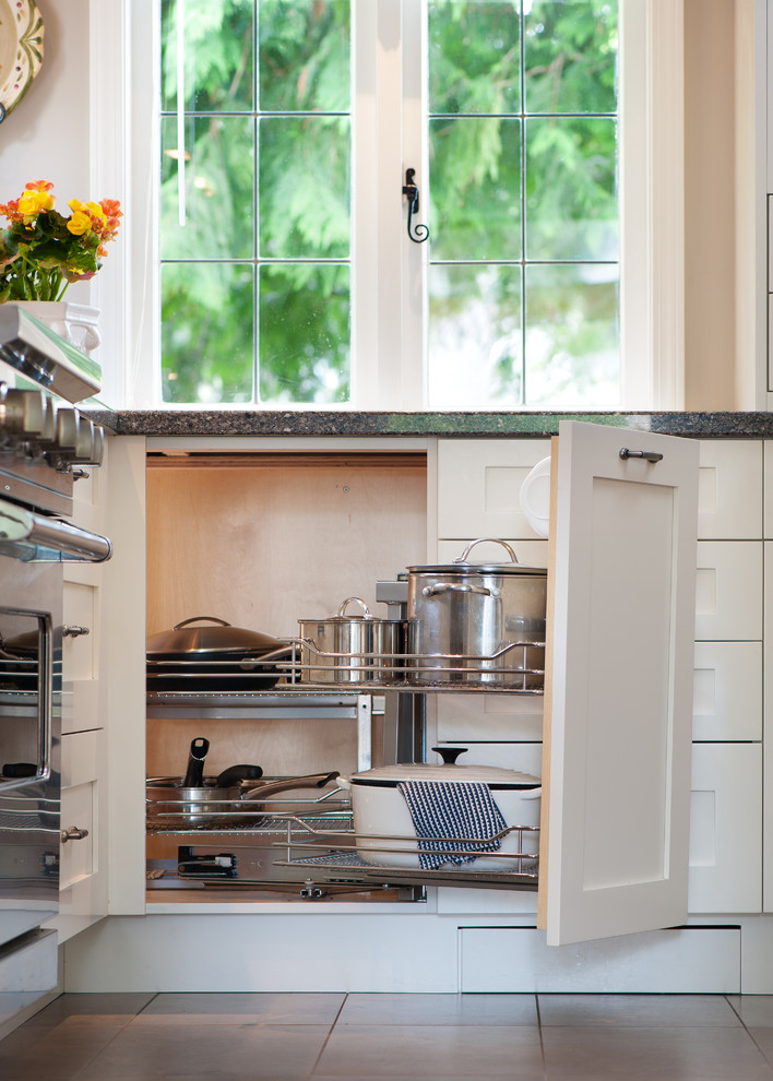 Moderne Wohnküche in L-Form mit Unterbauwaschbecken, Schrankfronten mit vertiefter Füllung, weißen Schränken, Granit-Arbeitsplatte, Küchenrückwand in Beige, Rückwand aus Glasfliesen und Küchengeräten aus Edelstahl in Vancouver