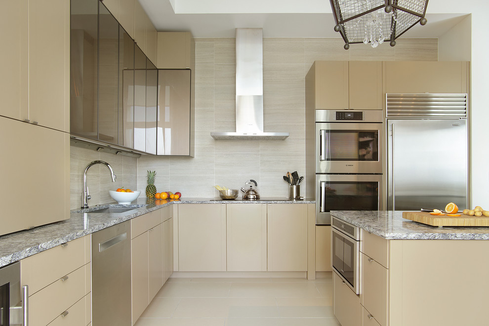 Example of a large trendy l-shaped porcelain tile and beige floor kitchen design in Other with flat-panel cabinets, beige cabinets, quartz countertops, beige backsplash, porcelain backsplash, stainless steel appliances, an island and an undermount sink