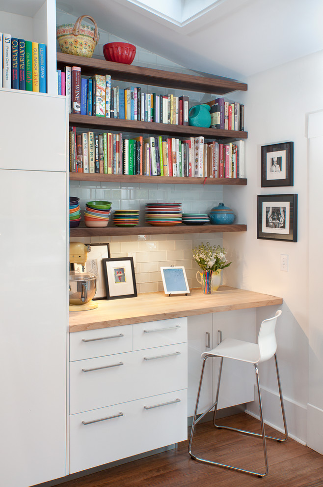 This is an example of a contemporary kitchen in Other with flat-panel cabinets, white cabinets, wood worktops, white splashback and metro tiled splashback.