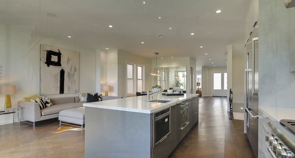This is an example of a large contemporary galley open plan kitchen in San Francisco with a submerged sink, flat-panel cabinets, grey cabinets, engineered stone countertops, stainless steel appliances and an island.
