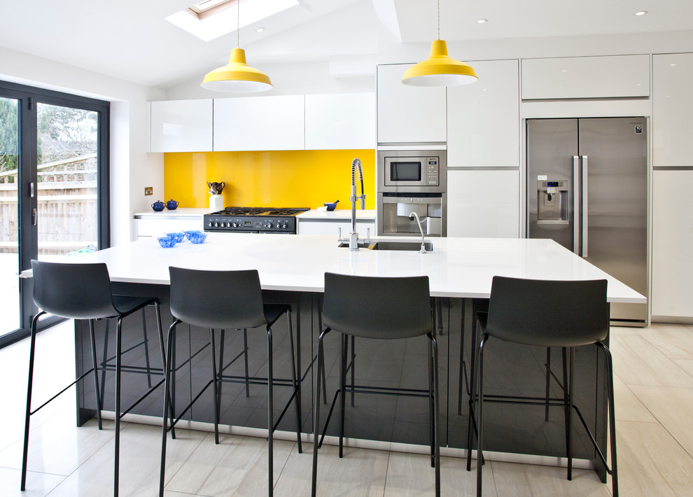 Esempio di una cucina minimal di medie dimensioni con ante lisce, ante bianche, paraspruzzi giallo, elettrodomestici in acciaio inossidabile, parquet chiaro, paraspruzzi con lastra di vetro e lavello sottopiano