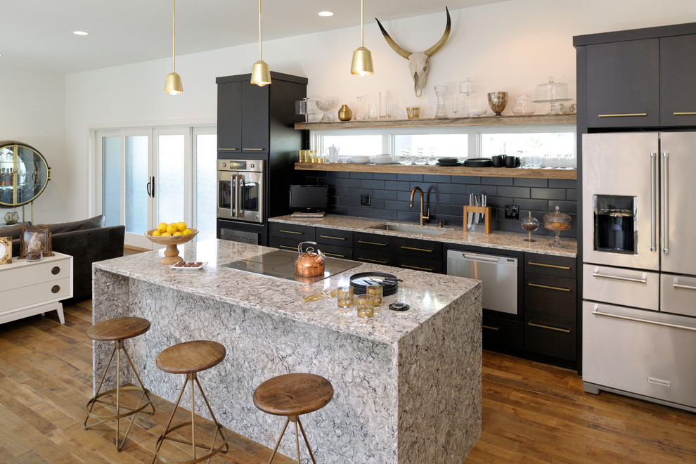 Example of a trendy single-wall medium tone wood floor open concept kitchen design in St Louis with an undermount sink, flat-panel cabinets, black cabinets, granite countertops, black backsplash, subway tile backsplash, stainless steel appliances and an island