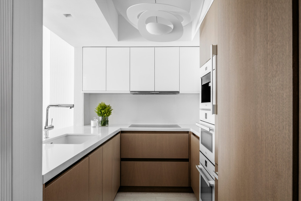 Trendy u-shaped kitchen photo in Miami with an undermount sink, flat-panel cabinets, medium tone wood cabinets, white appliances, a peninsula and white countertops