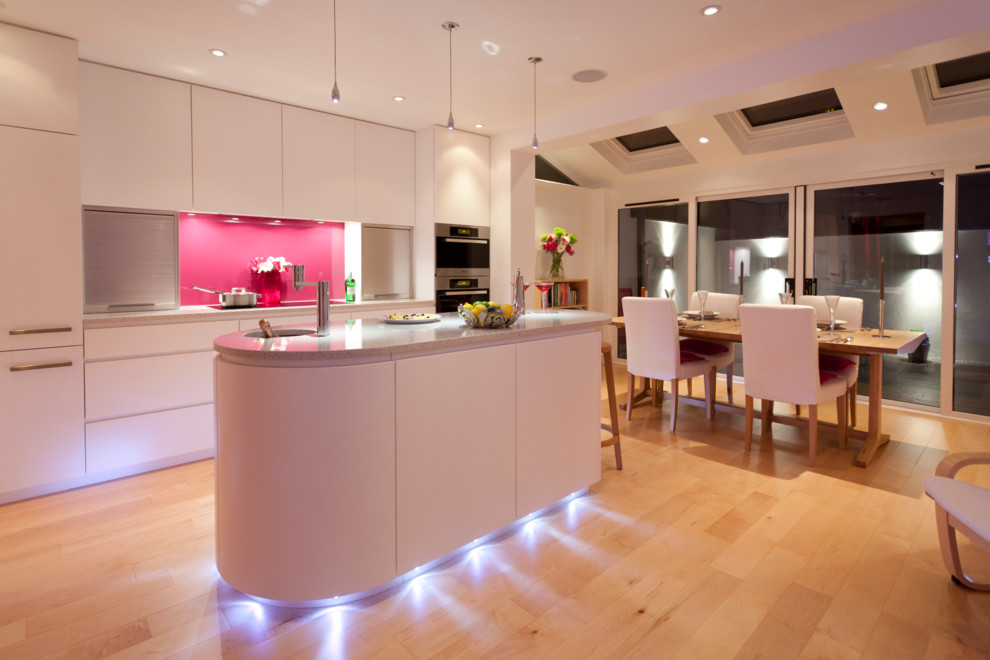 Immagine di una cucina design di medie dimensioni con lavello integrato, ante lisce, ante bianche, top in quarzite, paraspruzzi rosa, paraspruzzi con lastra di vetro, elettrodomestici in acciaio inossidabile e parquet chiaro