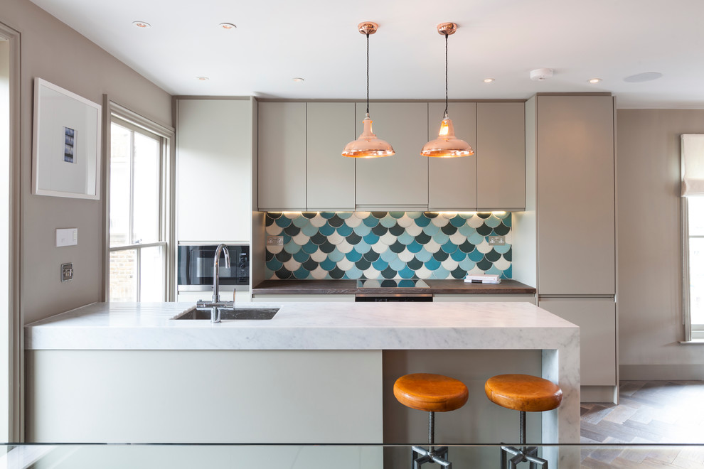 Inspiration for a medium sized contemporary galley kitchen in London with a submerged sink, flat-panel cabinets, grey cabinets, blue splashback, integrated appliances and medium hardwood flooring.