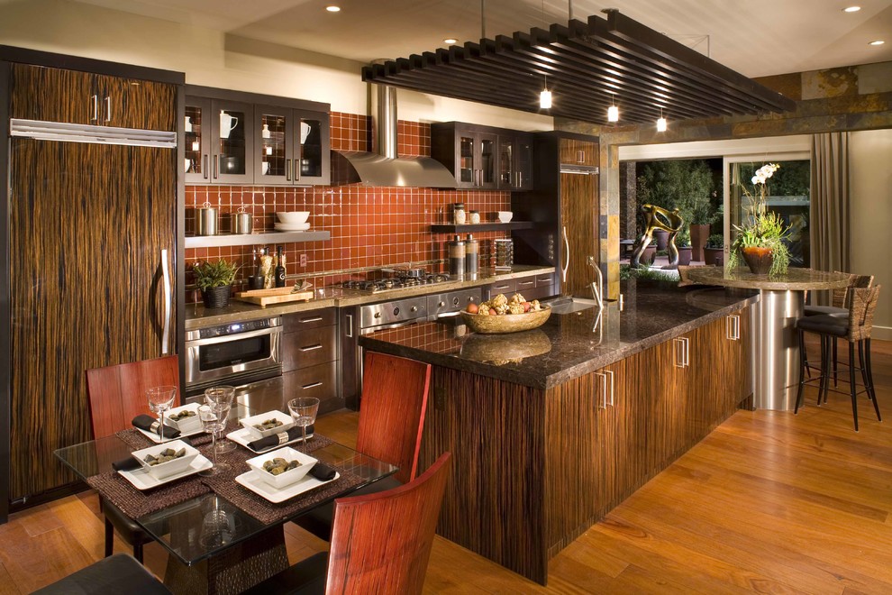 Inspiration pour une cuisine américaine parallèle design en bois foncé avec un placard à porte plane, une crédence marron, une crédence en céramique et un électroménager en acier inoxydable.