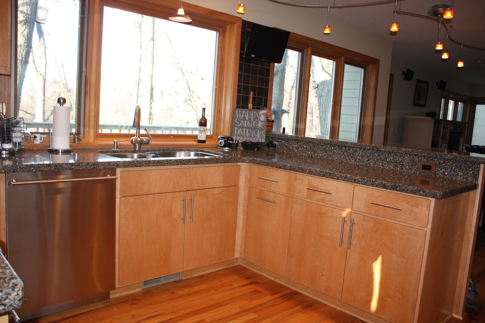 Bild på ett avskilt, litet funkis u-kök, med släta luckor, skåp i rostfritt stål, granitbänkskiva, grått stänkskydd, stänkskydd i porslinskakel, rostfria vitvaror, mellanmörkt trägolv och brunt golv