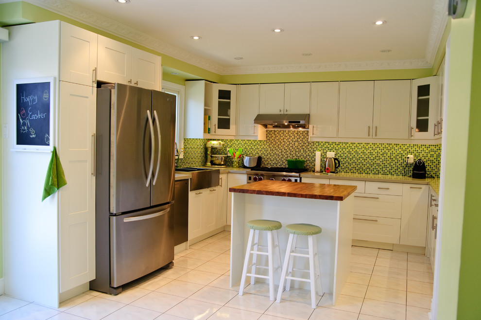 Bild på ett funkis l-kök, med en rustik diskho, skåp i shakerstil, vita skåp, grönt stänkskydd, stänkskydd i mosaik och rostfria vitvaror