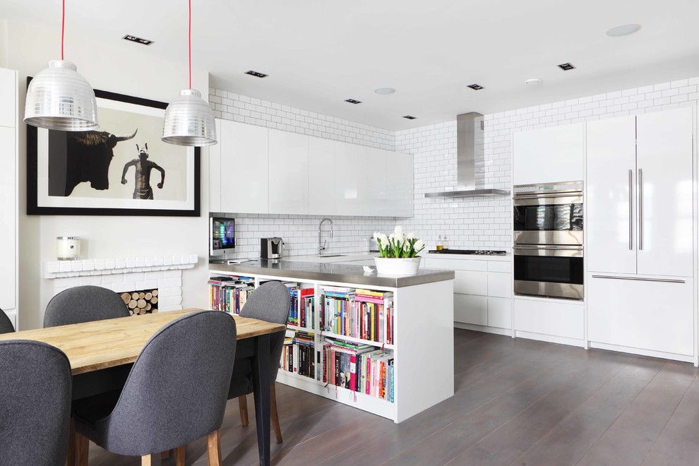 Contemporary u-shaped kitchen/diner in London with white cabinets, flat-panel cabinets, white splashback, metro tiled splashback and integrated appliances.