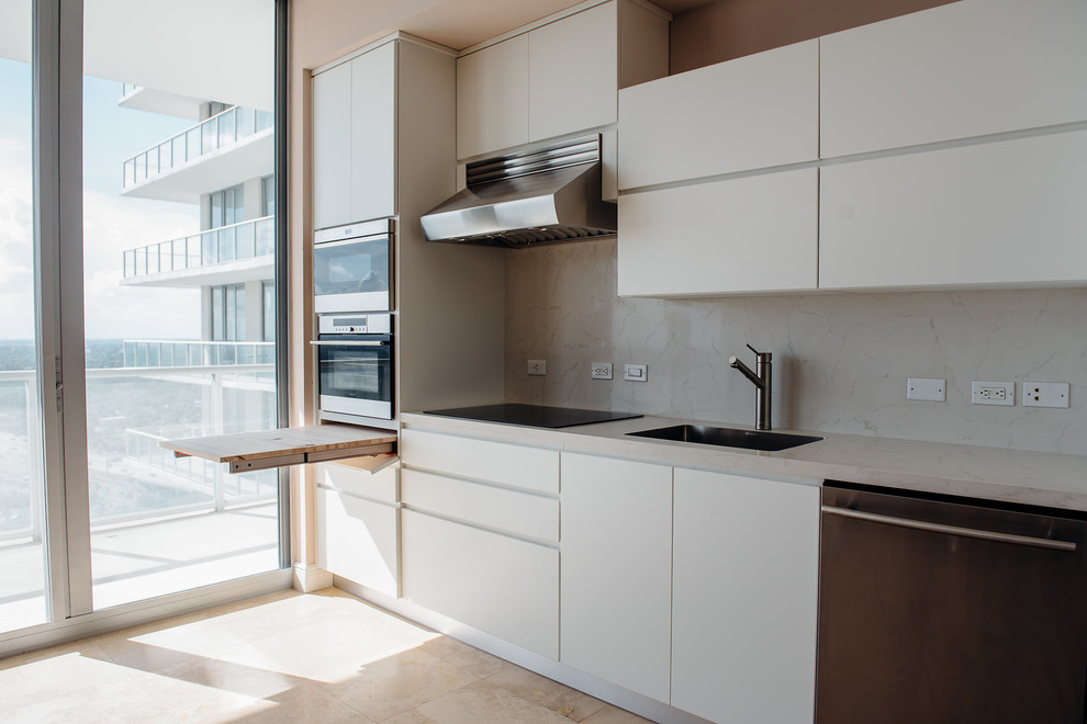 Ejemplo de cocina comedor lineal actual de tamaño medio con puertas de armario blancas, encimera de cuarzo compacto y electrodomésticos de acero inoxidable