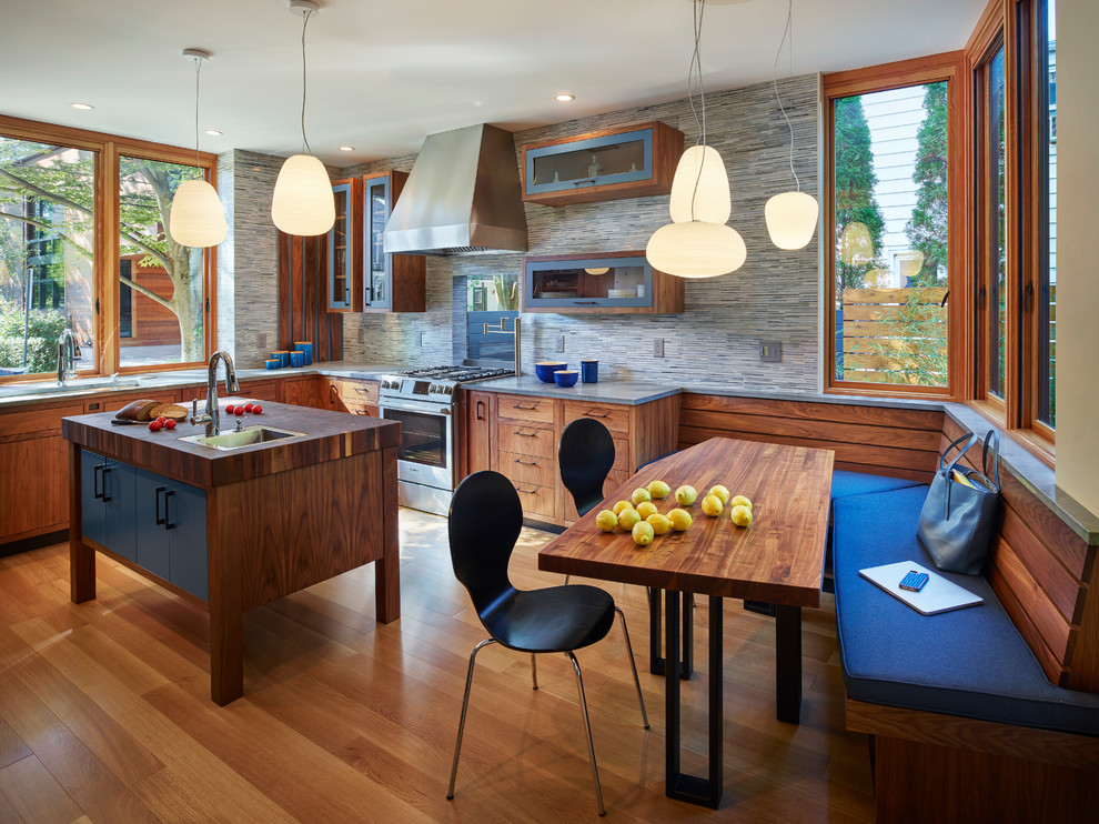 Moderne Wohnküche in L-Form mit flächenbündigen Schrankfronten, hellbraunen Holzschränken, Arbeitsplatte aus Holz, Küchengeräten aus Edelstahl, braunem Holzboden, Kücheninsel und braunem Boden in New York