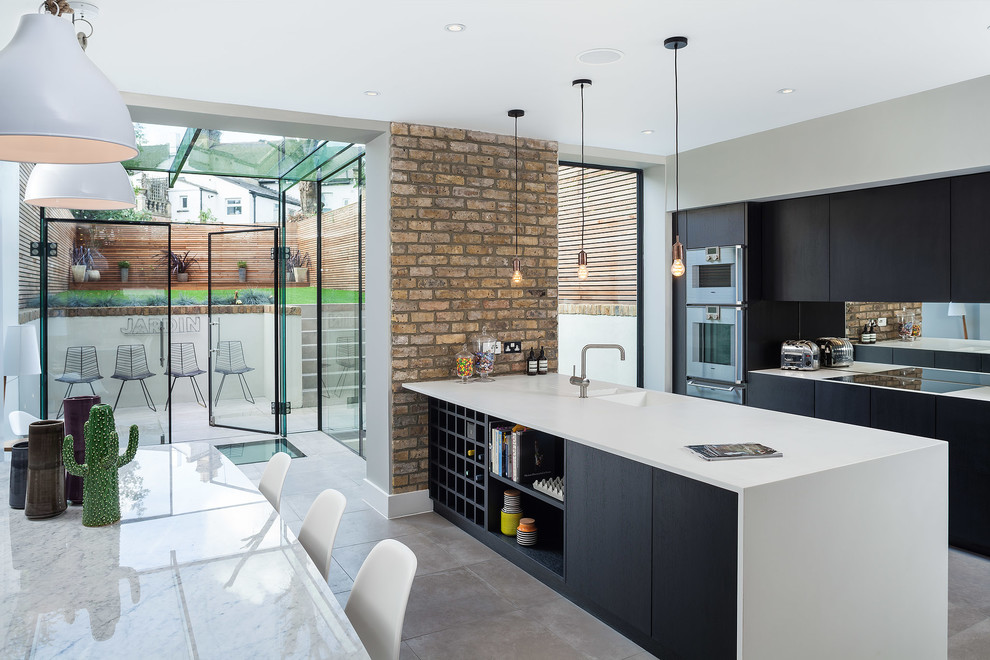 Contemporary kitchen/diner in London with an integrated sink, flat-panel cabinets and a breakfast bar.
