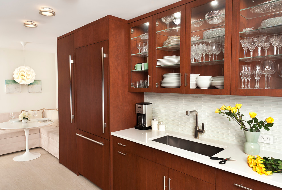 This is an example of a medium sized contemporary galley enclosed kitchen in New York with a submerged sink, flat-panel cabinets, dark wood cabinets, engineered stone countertops, white splashback, integrated appliances, porcelain flooring and no island.