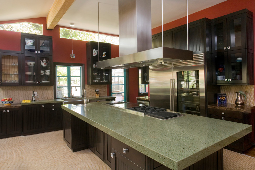 Example of a large trendy kitchen design in Los Angeles with a farmhouse sink, glass-front cabinets, black cabinets, terrazzo countertops, beige backsplash, mosaic tile backsplash, stainless steel appliances and an island