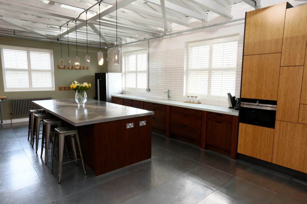 Cette photo montre une grande cuisine ouverte linéaire tendance en bois brun avec îlot, un évier posé, un placard à porte plane, un plan de travail en béton et un électroménager noir.
