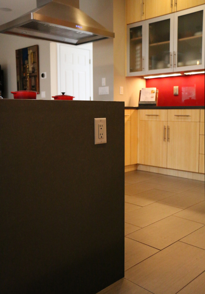 Foto de cocina actual de tamaño medio sin isla con armarios con paneles lisos, puertas de armario de madera clara, salpicadero rojo y electrodomésticos de acero inoxidable