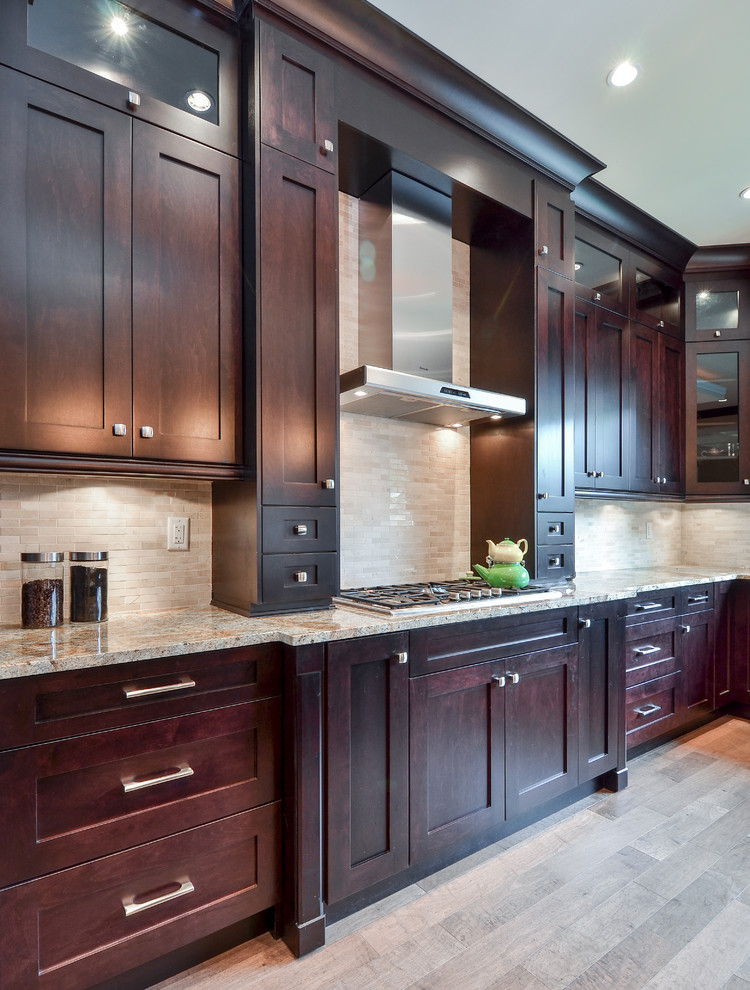 Example of a large trendy light wood floor eat-in kitchen design in Vancouver with shaker cabinets, dark wood cabinets, granite countertops, stainless steel appliances, beige backsplash, stone slab backsplash and an island