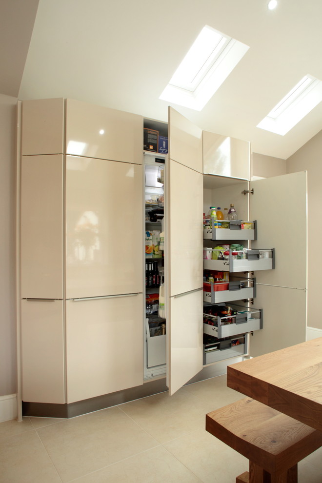 Ejemplo de cocina comedor actual con armarios con paneles lisos, puertas de armario beige y suelo beige