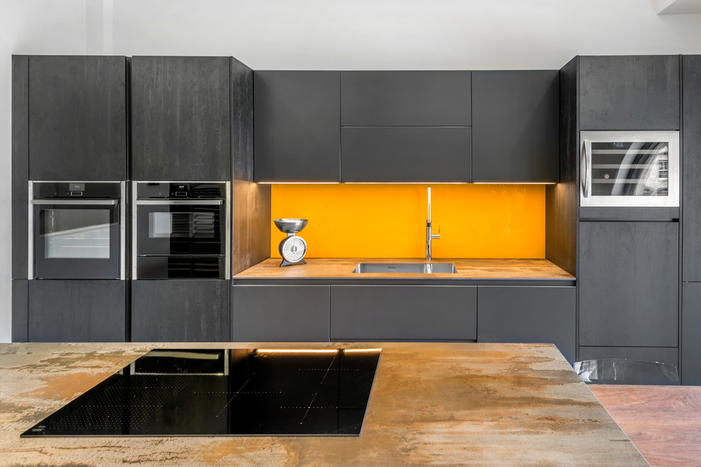 Große Moderne Wohnküche in U-Form mit Einbauwaschbecken, schwarzen Schränken, Glasrückwand, zwei Kücheninseln und grauem Boden in Sonstige