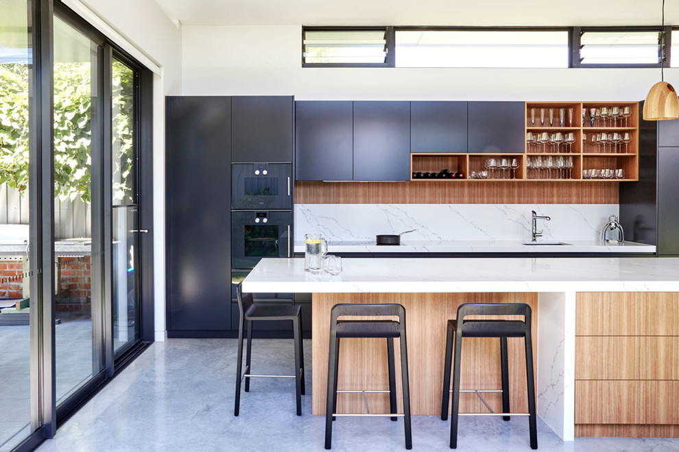 Photo of a large contemporary single-wall kitchen/diner in Sydney with a submerged sink, white splashback, black appliances, an island, grey floors, black cabinets, concrete flooring, engineered stone countertops, stone slab splashback and white worktops.