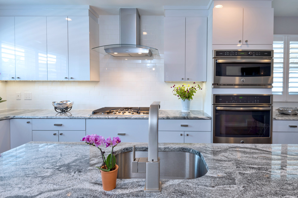 Mid-sized trendy l-shaped travertine floor eat-in kitchen photo in Philadelphia with an undermount sink, flat-panel cabinets, yellow cabinets, white backsplash, subway tile backsplash, stainless steel appliances, an island and laminate countertops