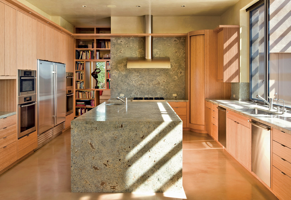 На фото: п-образная кухня в современном стиле с плоскими фасадами, техникой из нержавеющей стали, серым фартуком, фартуком из каменной плиты, светлыми деревянными фасадами и врезной мойкой с