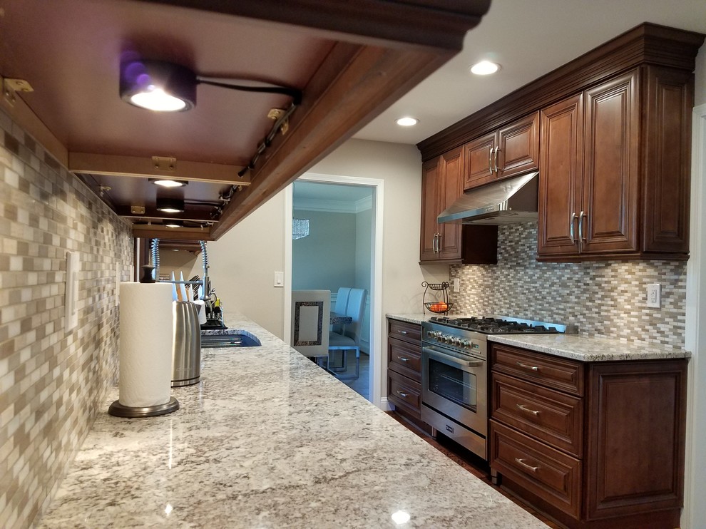 Mid-sized elegant galley dark wood floor enclosed kitchen photo in Atlanta with stainless steel appliances, a double-bowl sink, raised-panel cabinets, dark wood cabinets, granite countertops, multicolored backsplash, matchstick tile backsplash and no island