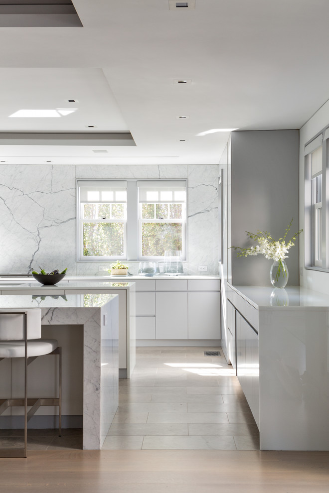Design ideas for a contemporary kitchen in New York with flat-panel cabinets, white cabinets, white splashback, stone slab splashback, medium hardwood flooring and multiple islands.