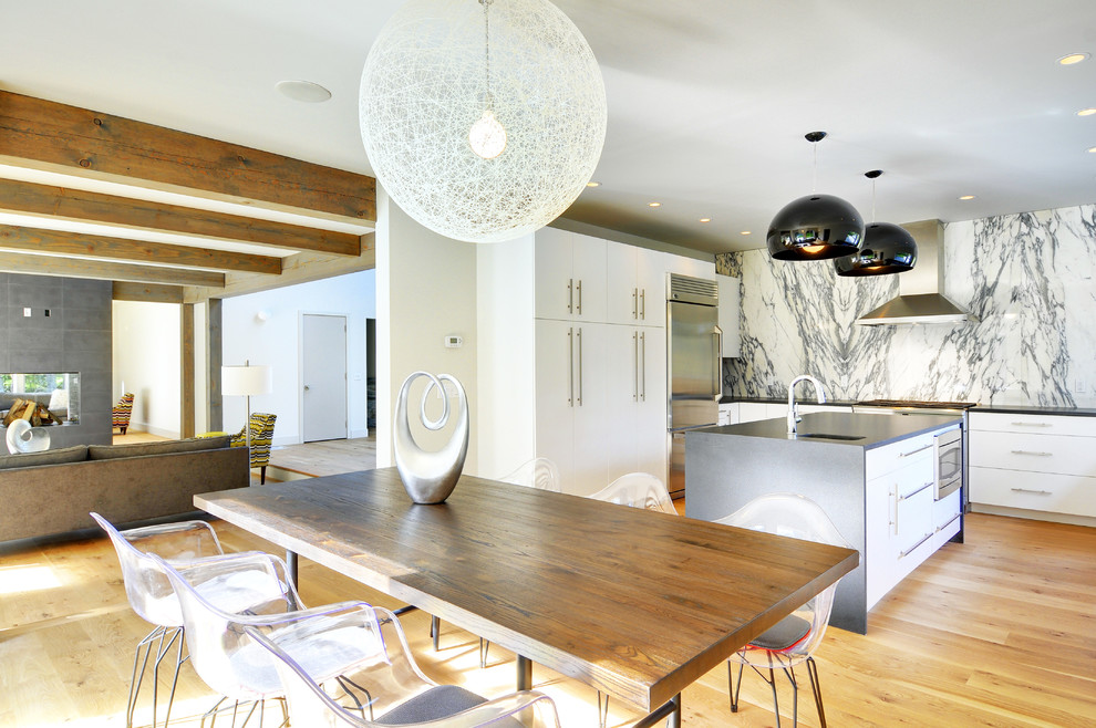 Exempel på ett stort modernt kök, med en undermonterad diskho, släta luckor, vita skåp, granitbänkskiva, vitt stänkskydd, stänkskydd i sten, rostfria vitvaror, ljust trägolv och en köksö