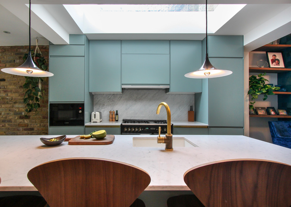 Contemporary galley kitchen in London with blue cabinets, quartz worktops, white splashback, marble splashback, light hardwood flooring, an island and a submerged sink.