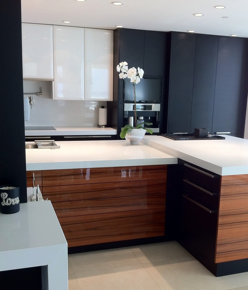 Medium sized contemporary u-shaped kitchen/diner in Miami with flat-panel cabinets, white splashback, stainless steel appliances, an island, a submerged sink, black cabinets, engineered stone countertops, stone slab splashback and porcelain flooring.