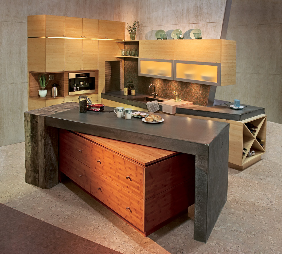 Cette image montre une cuisine design en bois clair avec un placard à porte plane, un plan de travail en béton, une crédence verte, une crédence en feuille de verre et un sol en liège.