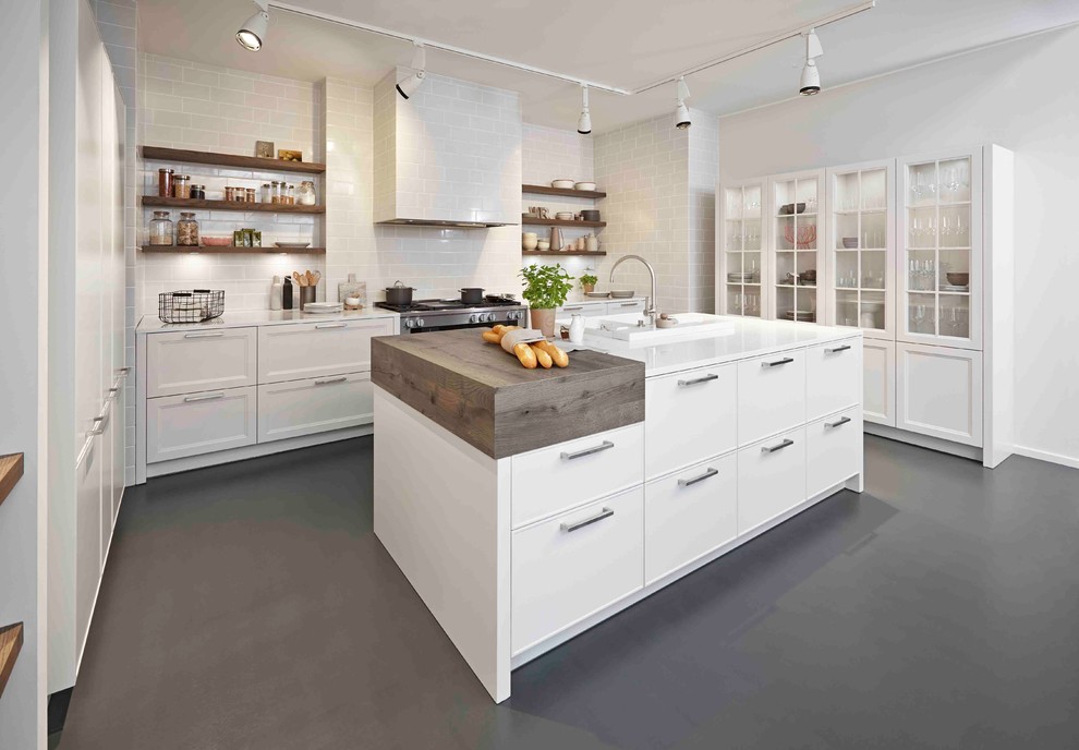 Inspiration for a contemporary l-shaped kitchen/diner in Detroit with recessed-panel cabinets, white cabinets, white splashback, metro tiled splashback, stainless steel appliances, an island, a built-in sink, engineered stone countertops and concrete flooring.