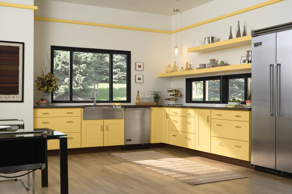 Klassische Wohnküche ohne Insel in L-Form mit Landhausspüle, Schrankfronten im Shaker-Stil, gelben Schränken, Küchengeräten aus Edelstahl und dunklem Holzboden in Denver