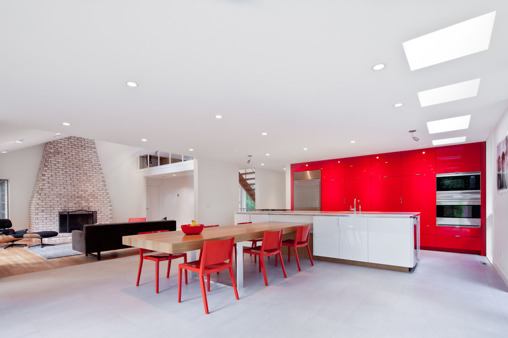 Ejemplo de cocina contemporánea de tamaño medio abierta con fregadero bajoencimera, armarios con paneles lisos, puertas de armario rojas, electrodomésticos de acero inoxidable, una isla y suelo gris