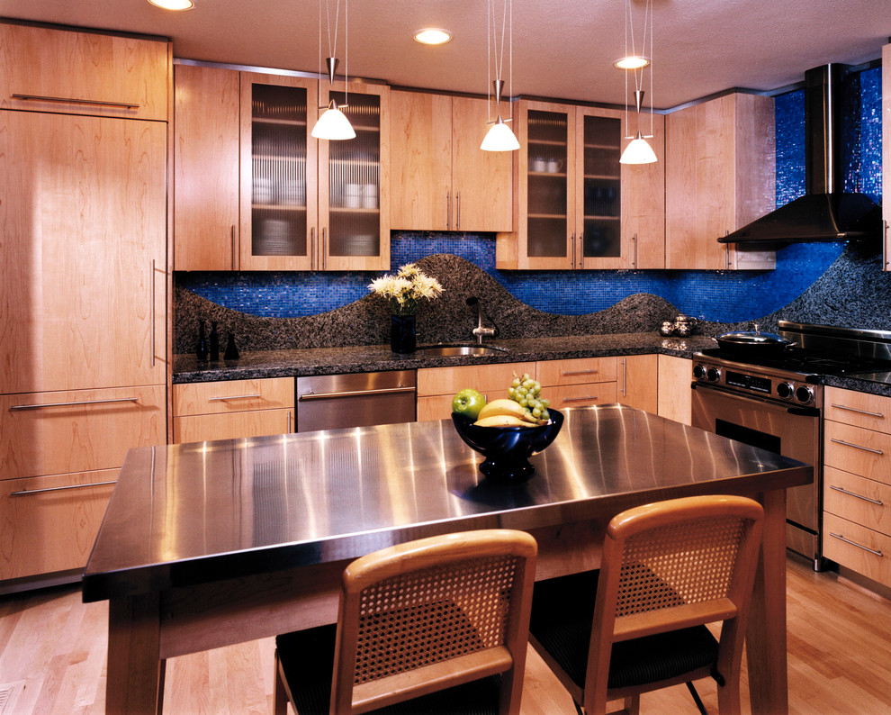 Пример оригинального дизайна: кухня в современном стиле с столешницей из нержавеющей стали, плоскими фасадами, светлыми деревянными фасадами, синим фартуком, фартуком из плитки мозаики и техникой из нержавеющей стали