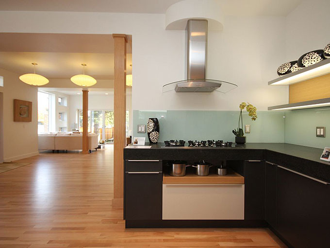Example of a mid-sized minimalist u-shaped light wood floor kitchen design in Calgary with a double-bowl sink, flat-panel cabinets, black cabinets, granite countertops, blue backsplash, glass sheet backsplash, stainless steel appliances and a peninsula