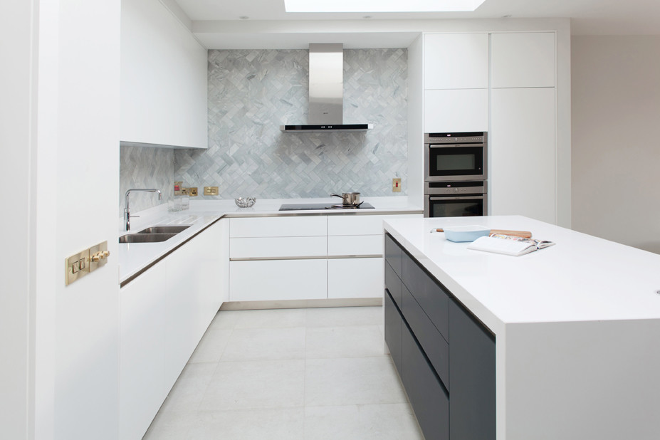 This is an example of a large contemporary l-shaped open plan kitchen in Dublin with a double-bowl sink, flat-panel cabinets, white cabinets, laminate countertops, grey splashback, stone tiled splashback, stainless steel appliances, cement flooring, an island, grey floors and white worktops.