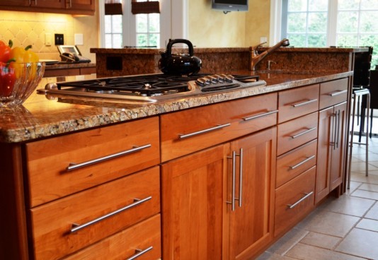 Exemple d'une grande cuisine américaine tendance en L et bois brun avec un évier encastré, un placard à porte shaker, une crédence beige, une crédence en céramique, un électroménager en acier inoxydable et îlot.