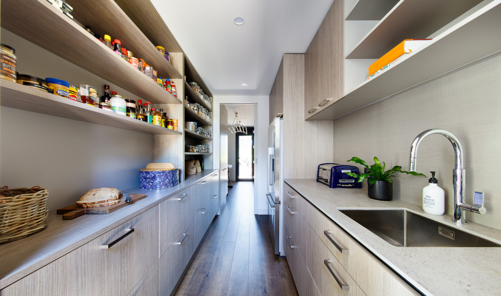 Example of a large trendy galley medium tone wood floor and brown floor kitchen pantry design in Melbourne with a drop-in sink, flat-panel cabinets, light wood cabinets, quartz countertops, stainless steel appliances and white countertops