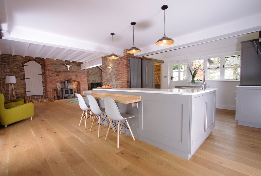 Inspiration for a large contemporary l-shaped open plan kitchen in Surrey with shaker cabinets, grey cabinets, granite worktops, stainless steel appliances, medium hardwood flooring, a breakfast bar and multicoloured worktops.